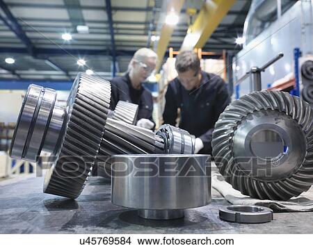 Picture - Male and female engineers assembling industrial gearbox in engineering factory. Fotosearch