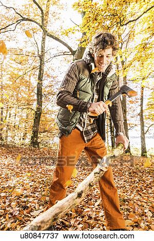 Stock Photo - Man chopping log with axe. Fotosearch