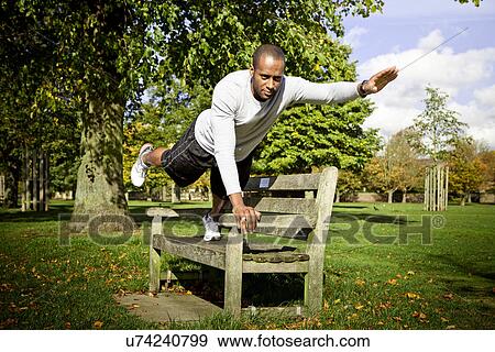 Man in plank position on park bench View Large Photo Image Stock Photo - Man in plank position on park bench. Fotosearch