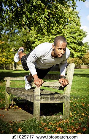 Man in plank position on park bench View Large Photo Image Stock Photo - Man in plank position on park bench. Fotosearch