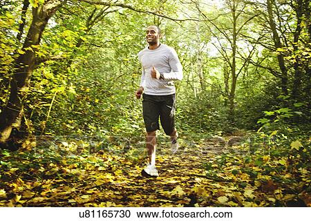 Stock Image - Man jogging in woods. Fotosearch