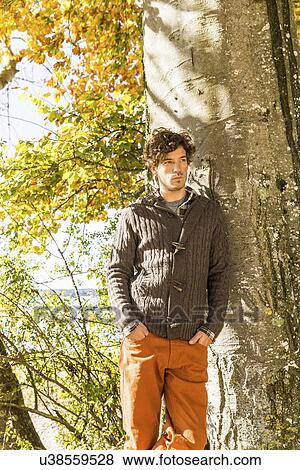 Man leaning against tree trunk View Large Photo Image Stock Photo - Man leaning against tree trunk. Fotosearch