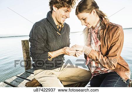 Man putting engagement ring on woman View Large Photo Image Stock Photo - Man putting engagement ring on woman. Fotosearch