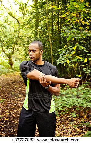 Man stretching arms in woods View Large Photo Image Stock Image - Man stretching arms in woods. Fotosearch