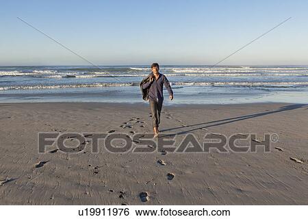 Stock Photograph - Man walking on beach. Fotosearch