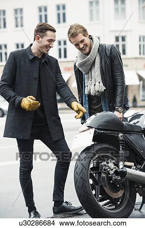 Picture - Man with friend pointing at motorcycle. Fotosearch
