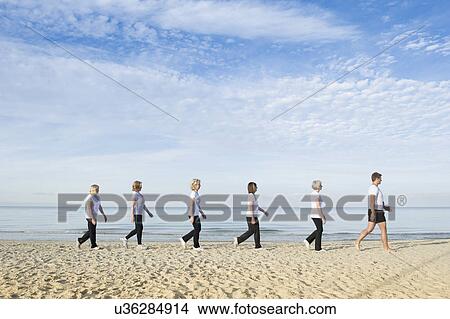 Picture - Mature and senior women with their trainer walking along beach. Fotosearch