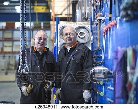 Stock Image - Mature engineers working in engineering factory, portrait. Fotosearch