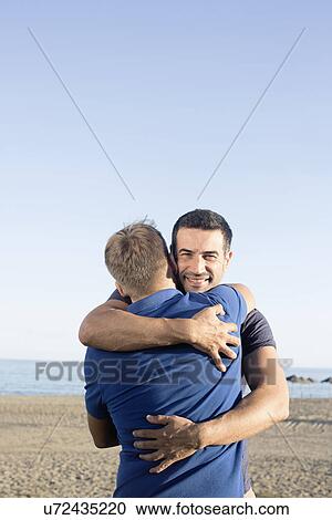 Mature male couple hugging on beach View Large Photo Image Stock Image - Mature male couple hugging on beach. Fotosearch