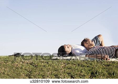 Mature male couple lying on picnic blanket in park View Large Photo Image Stock Photo - Mature male couple lying on picnic blanket in park. Fotosearch