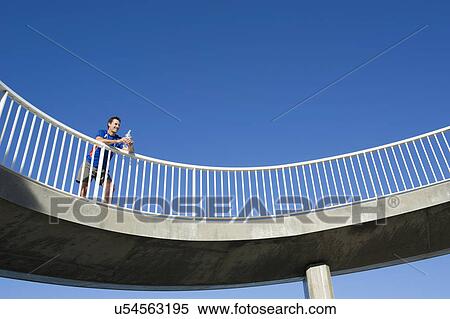 Mature male runner holding water bottle on footbridge View Large Photo Image Stock Photography - Mature male runner holding water bottle on footbridge. Fotosearch