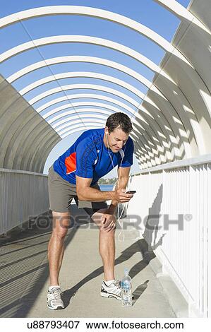 Mature male runner looking at his MP3 player View Large Photo Image Stock Photo - Mature male runner looking at his MP3 player. Fotosearch