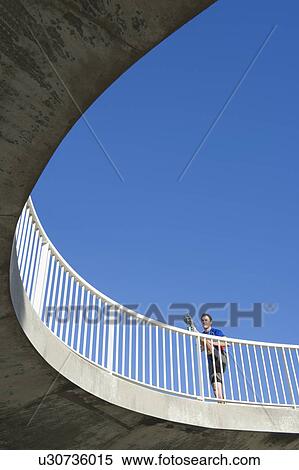 Mature male runner stretching legs on footbridge View Large Photo Image Stock Photography - Mature male runner stretching legs on footbridge. Fotosearch