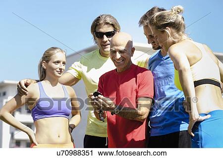 Stock Image - Mature male trainer and a group of adult runners. Fotosearch