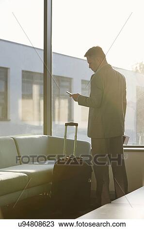 Stock Image - Mature man in airport using cell phone. Fotosearch