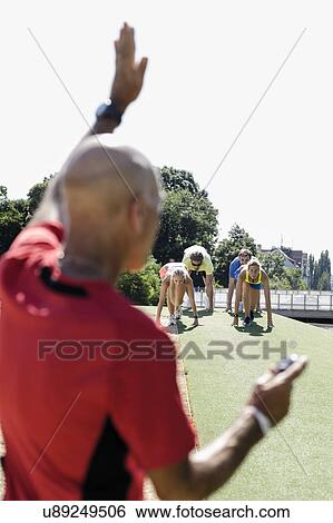 Mature man preparing a group of adult runners at start line View Large Photo Image Stock Photograph - Mature man preparing a group of adult runners at start line. Fotosearch
