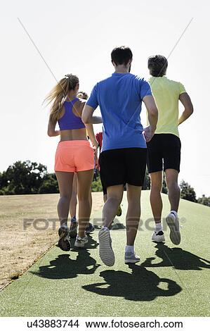 Picture - Mature trainer running with group of adults in park. Fotosearch