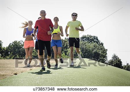Stock Photo - Mature trainer running with group of adults. Fotosearch