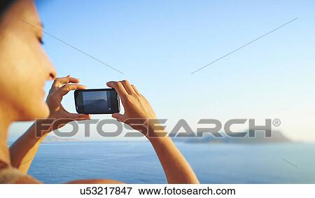 Stock Photo - Mature woman checking photographs on smartphone, Kas, Turkey. Fotosearch