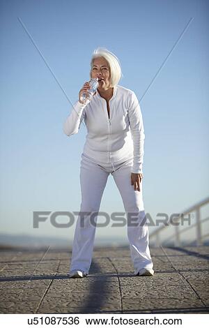 Mature woman drinking water on walk View Large Photo Image Stock Photograph - Mature woman drinking water on walk. Fotosearch