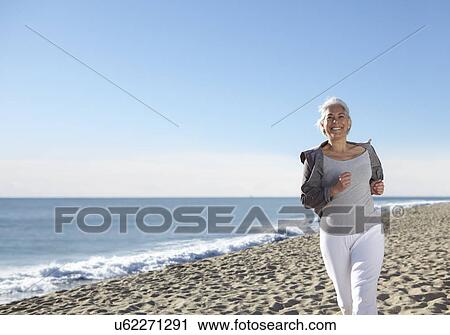 Mature woman jogging on beach View Large Photo Image Stock Image - Mature woman jogging on beach. Fotosearch