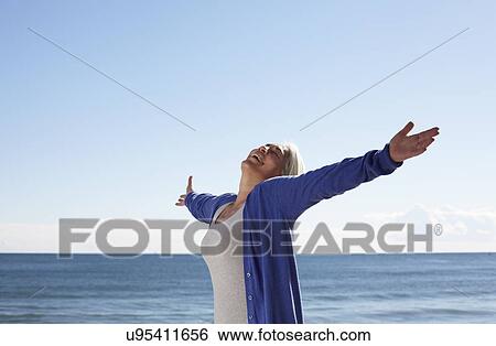 Mature woman on beach with arms outspread View Large Photo Image Stock Photograph - Mature woman on beach with arms outspread. Fotosearch