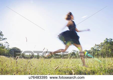 Stock Photography - Mid adult woman running through summer meadow. Fotosearch