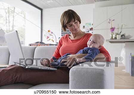 Mother and baby boy reclining on sofa with laptop View Large Photo Image Stock Image - Mother and baby boy reclining on sofa with laptop. Fotosearch