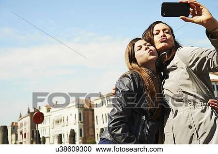 Mother and daughter taking selfie on smartphone, Venice, Italy View Large Photo Image Stock Image - Mother and daughter taking selfie on smartphone, Venice, Italy. Fotosearch