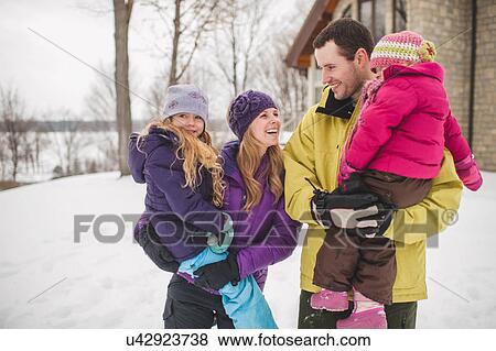 Stock Photo - Mother and father carrying daughters in snow. Fotosearch