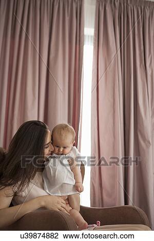 Mother playing with baby in armchair View Large Photo Image Stock Image - Mother playing with baby in armchair. Fotosearch