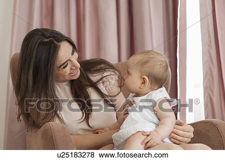 Mother playing with baby in armchair View Large Photo Image Stock Photo - Mother playing with baby in armchair. Fotosearch
