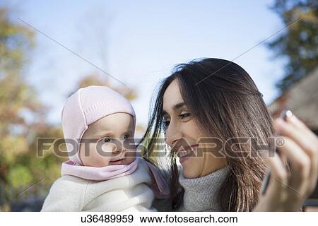 Mother showing cellular phone to baby View Large Photo Image Stock Photo - Mother showing cellular phone to baby. Fotosearch