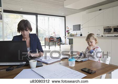 Mother with female toddler working on computer at kitchen table View Large Photo Image Stock Image - Mother with female toddler working on computer at kitchen table. Fotosearch