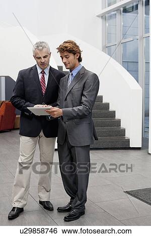 Office manager chatting with colleague in office atrium View Large Photo Image Stock Photograph - Office manager chatting with colleague in office atrium. Fotosearch