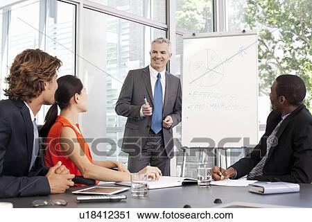 Stock Image - Office manager giving flipchart presentation at meeting. Fotosearch