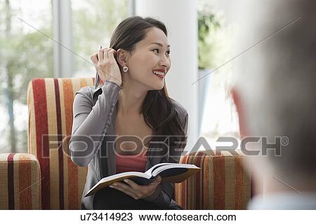 Stock Image - Office worker making notes at meeting. Fotosearch