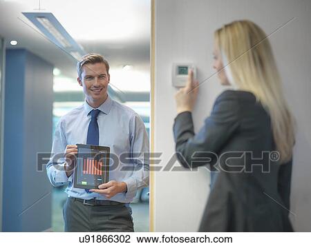 Office workers adjusting heating thermostat and recording information on digital tablet View Large Photo Image Stock Image - Office workers adjusting heating thermostat and recording information on digital tablet. Fotosearch