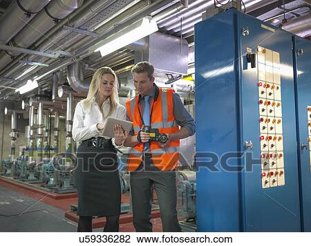 Stock Image - Office workers using digital tablet and camera to check efficiency of office heating in boiler room. Fotosearch