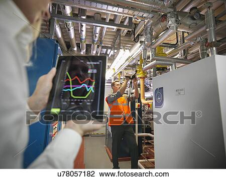Office workers using digital tablet and camera to check efficiency of office heating in boiler room View Large Photo Image Stock Image - Office workers using digital tablet and camera to check efficiency of office heating in boiler room. Fotosearch