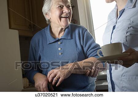 Personal care assistant carrying cup of tea for senior woman View Large Photo Image Stock Image - Personal care assistant carrying cup of tea for senior woman. Fotosearch