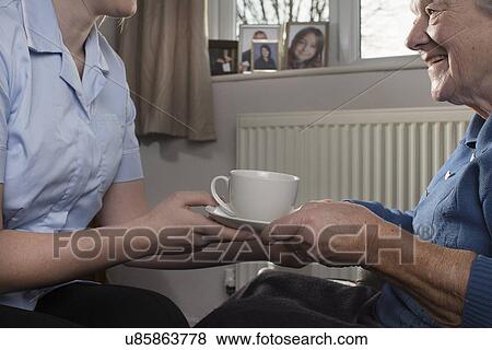 Personal care assistant handing senior woman cup of tea View Large Photo Image Stock Photo - Personal care assistant handing senior woman cup of tea. Fotosearch