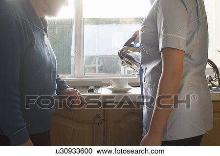 Personal care assistant making cup of tea for senior woman View Large Photo Image Stock Image - Personal care assistant making cup of tea for senior woman. Fotosearch