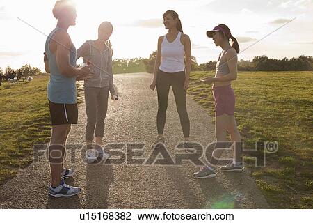 Stock Image - Personal trainer with group of clients preparing for run. Fotosearch