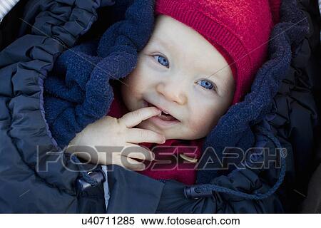 Stock Photography - Portrait of baby girl in sleeping bag wearing hat. Fotosearch