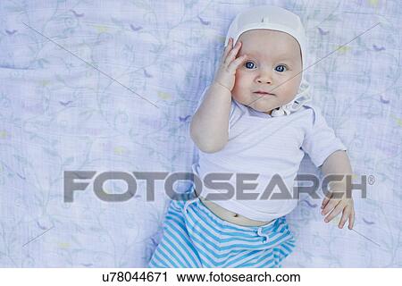 Stock Image - Portrait of baby girl touching face. Fotosearch