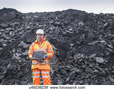 Stock Photo - Portrait of coal miner holding coal in surface coal mine. Fotosearch