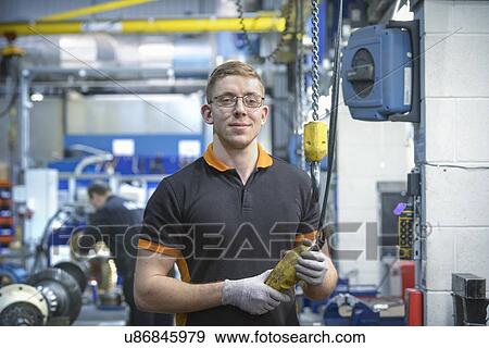 Stock Photo - Portrait of engineering apprentice in engineering factory, smiling. Fotosearch