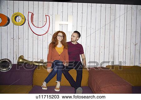 Stock Image - Portrait of funky young couple sitting on seats in club. Fotosearch