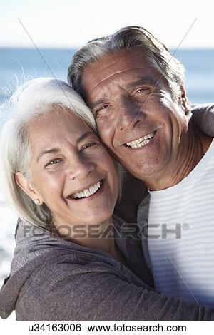 Portrait of happy couple by seaside View Large Photo Image Stock Photograph - Portrait of happy couple by seaside. Fotosearch